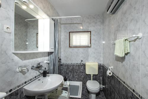 a bathroom with a sink and a toilet and a mirror at Poolhouse Domus in Solin