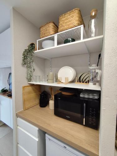 une cuisine avec des étagères blanches et un four micro-ondes noir dans l'établissement Studio plein centre, à Aix-en-Provence