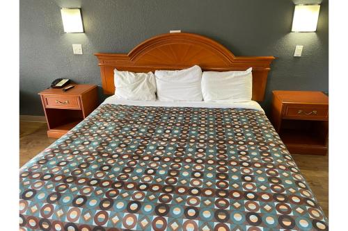 a bed in a hotel room with two night stands at Budget Inn Greenville By Hotel O I-85 in Greenville