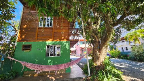 a hammock in front of a house with a tree at Residencial Recanto Paraíso BC - Chalé da Árvore in Balneário Camboriú