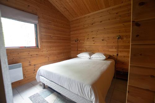une chambre avec un lit dans une cabane en bois dans l'établissement Chalet village vacances, à Mauroux