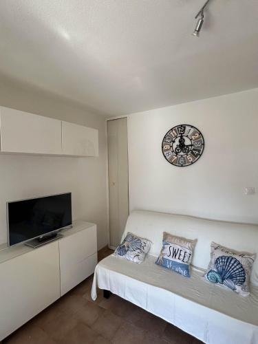 une chambre blanche avec une horloge sur le mur dans l'établissement Mazet climatisé avec piscine & tennis Résidence calme proche Lavandou, à Bormes-les-Mimosas