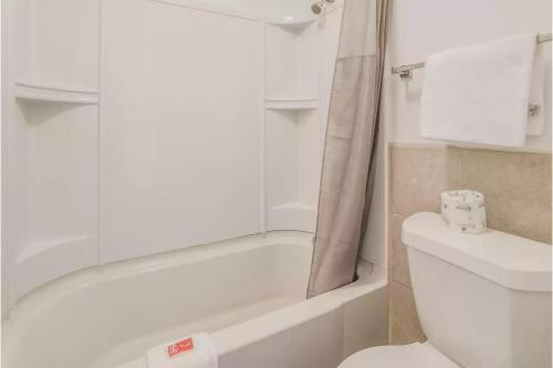 a bathroom with a white tub and a toilet at Budget Inn Greenville By Hotel O I-85 in Greenville