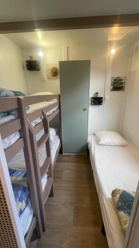 Cette petite chambre comprend 2 lits superposés et une porte. dans l'établissement Chalet climatisé en Haute-Corse 500m plage - camping Marina di Sorbo, à Sorbo-Ocagnano