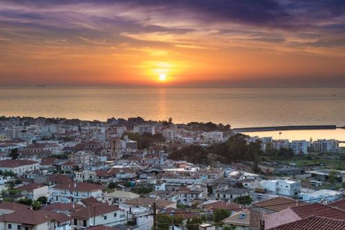 a city with the sun setting over the ocean at Rodia apartment in Kyparissia
