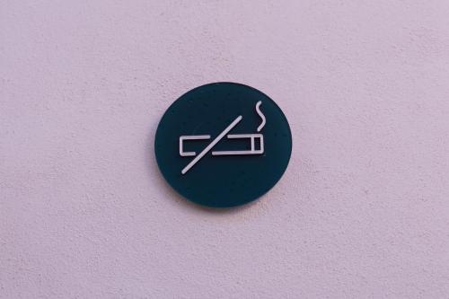 a black sign on a pink wall with a smoking symbol at El Sho - Hotel orgánico in Bucerías
