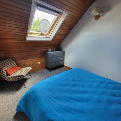 une chambre avec un lit bleu et une fenêtre dans l'établissement La maison d'étape, à Saint-Évarzec