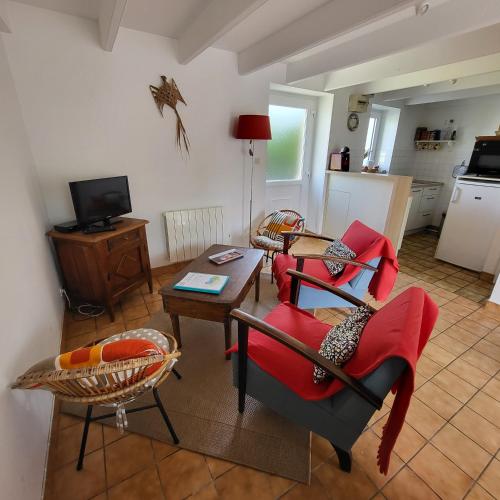 un salon avec des chaises rouges et une table dans l'établissement La maison d'étape, à Saint-Évarzec
