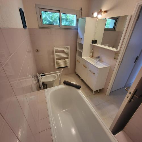 une salle de bain blanche avec une baignoire et un lavabo dans l'établissement FOUESNANT La Maison de Gigi, à 2 minutes de la plage de KERLER, à Fouesnant