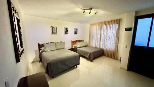 a hotel room with two beds and a window at Casa Mia Nanacamilpa Luciernagas in Nanacamilpa