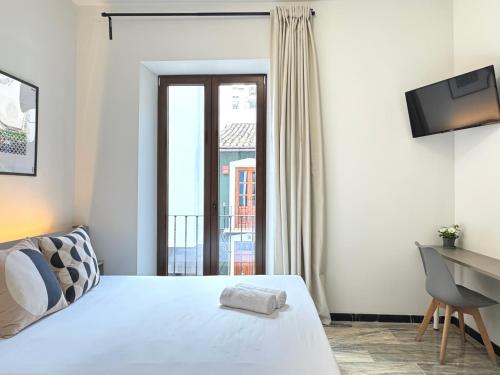 a bedroom with a bed and a desk and a window at Casa Azhuma in Granada