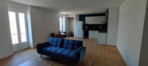 un salon avec un canapé bleu et une cuisine dans l'établissement Appartement 3 chambres vallée du Lot, à Capdenac-Gare