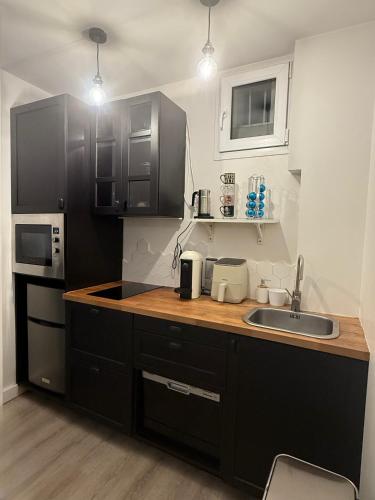 - une cuisine avec des placards noirs et un évier dans l'établissement Appartement T2 cooconing, Paris 11ème, à Paris