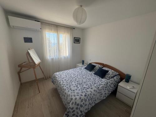 a bedroom with a bed with blue pillows and a window at REZ de VILLA Entre Mer et Maquis Appartement indépendant in Coti-Chiavari
