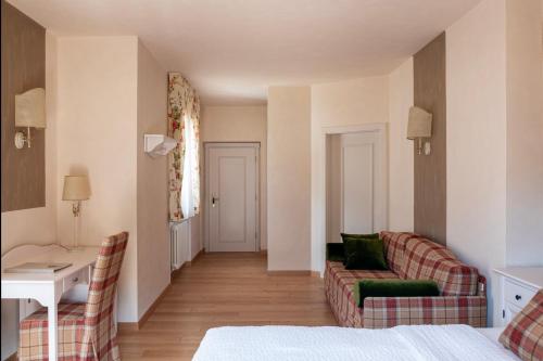 a hotel room with a bed and a couch and a table at Hotel Du Lac in Molveno