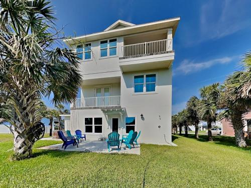 a white house with blue chairs in front of it at Atlantic Beach House in Flagler Beach