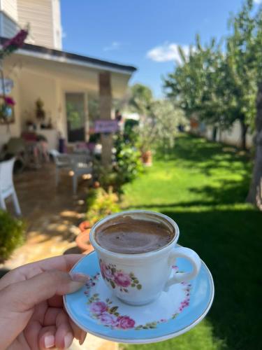 a person holding a cup of coffee on a plate at Villa İnci in Cesme