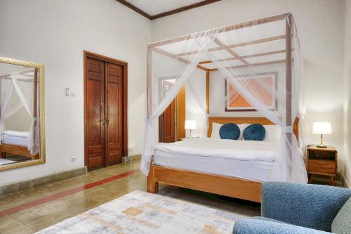 a bedroom with a canopy bed and a mirror at Entire Heritage Villa Family friendly in the Center of Yogya with Swimming Pool - Up to 9 people in Yogyakarta