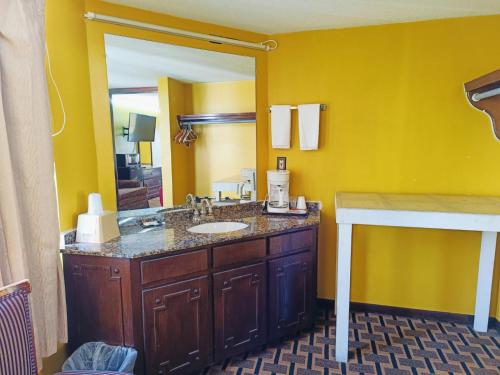 a bathroom with a sink and a mirror at Hotel O Victorian Inn Athens TX in Athens
