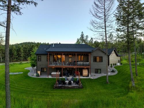 a large house with a large yard with green grass at Luxe Lakeside New Build by Flathead Lake Speakeasy in Somers