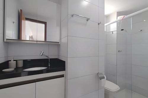 ein weißes Badezimmer mit Waschbecken und Spiegel in der Unterkunft Caribbean Blue - Jardim Oceania in João Pessoa