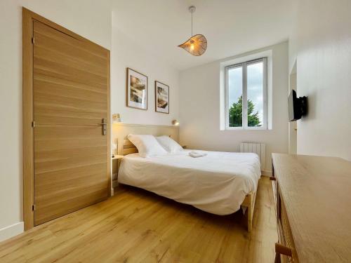 a bedroom with a large bed and a wooden door at La Rose des Marais - Renovated & Fully Equipped House in Houesville