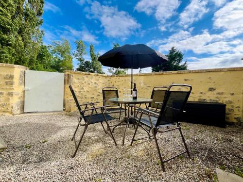 a table and two chairs with an umbrella at La Rose des Marais - Renovated & Fully Equipped House in Houesville
