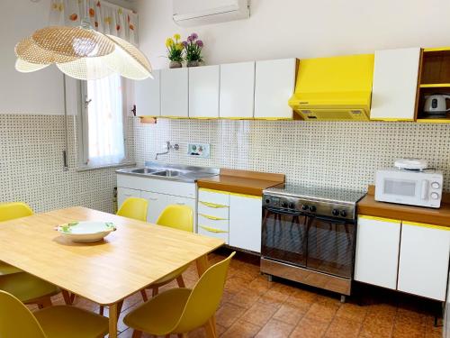 eine Küche mit weißen Schränken, einem Tisch und einer Mikrowelle in der Unterkunft Appartamenti Tina Paolini 2 con terrazzo in Castiglione della Pescaia