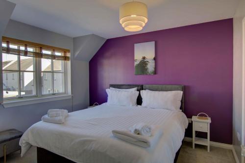 a purple bedroom with a large bed with towels on it at 3 Mackay Road, Dornoch in Dornoch