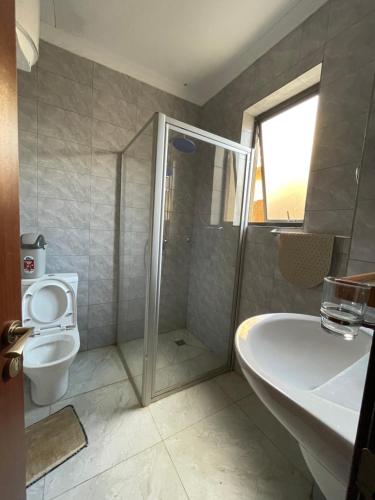 a bathroom with a shower and a toilet and a sink at Cozy Home-Rusororo-near airport in Kigali