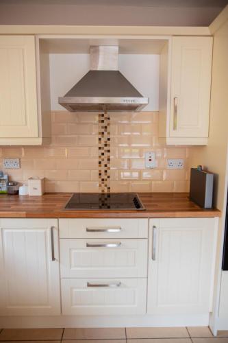 a kitchen with white cabinets and a range hood at An Garaiste in Rosscarbery