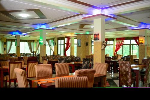 uma sala de jantar com mesas, cadeiras e luzes em Bunyonyi Safaris Resort em Kabale