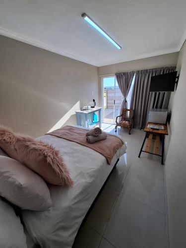 a bedroom with a bed and a desk and a window at Addo River Den in Gqeberha