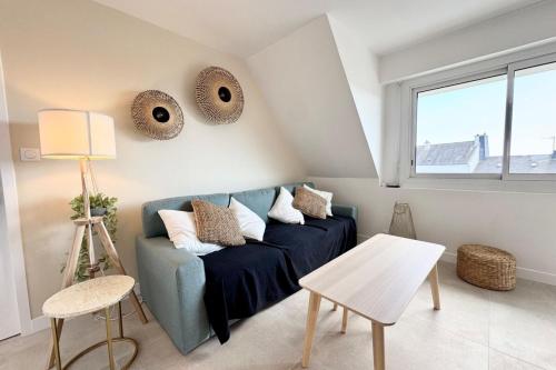 un salon avec un canapé bleu et une fenêtre dans l'établissement T3 neuf entre calme et bord de mer - Balcon, à Ploemeur