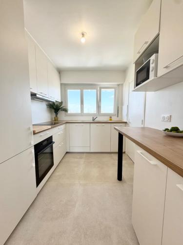 une cuisine avec des armoires blanches et un comptoir en bois dans l'établissement T3 neuf entre calme et bord de mer - Balcon, à Ploemeur