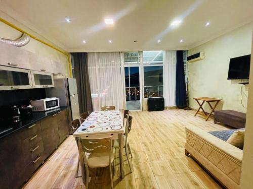 a kitchen and living room with a table and a couch at Batumi seaside Magnolia in Batumi