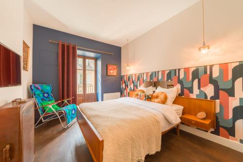 a bedroom with a large bed and a green chair at Les Seventies - Confort Vintage proche gare in Chambéry