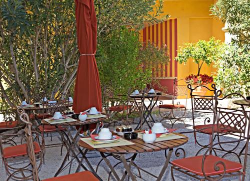 an outdoor patio with tables and chairs and an umbrella at La Bastide Du Port - Hôtel de Charme in Saint-Tropez