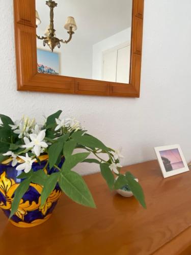 a vase of flowers on a table with a mirror at Brisa y Mar in Punta Umbría