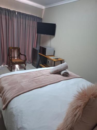 a bedroom with a bed with a desk and a chair at Addo River Den in Gqeberha