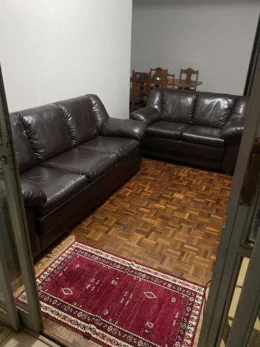 a black leather couch in a living room with a rug at Apartamento Zona 7 Maringá in Maringá