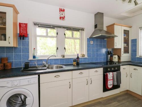 a kitchen with a sink and a washing machine at Tower Lodge in Dalmally