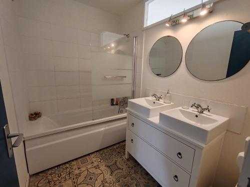 une salle de bain avec deux lavabos, une baignoire et un miroir dans l'établissement les Clés du lys, à Périgueux