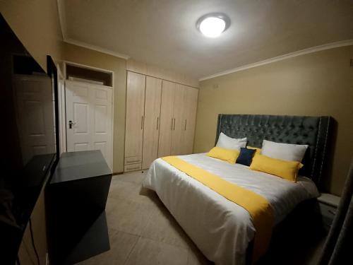 a bedroom with a bed with two yellow pillows at Ivy Cottage in Harare