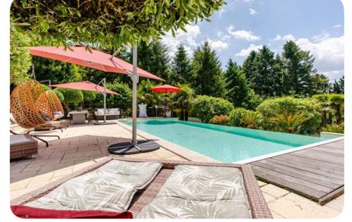 une piscine avec deux chaises longues et un parasol dans l'établissement Gîte 1 à 4 personnes Rez de jardin de la villa piscine jacuzzi sauna Fitness à partager, à Sarlat-la-Canéda