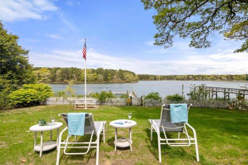 three chairs and a table in the grass near a lake at Waterfront Incredible Views and Private Dock in Yarmouth