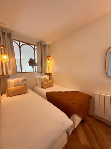 deux lits dans une chambre avec une fenêtre dans l'établissement Les Iles Bauloises, à La Baule