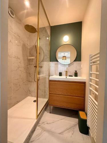 La salle de bains est pourvue d'une douche et d'un lavabo avec un miroir. dans l'établissement Les Iles Bauloises, à La Baule