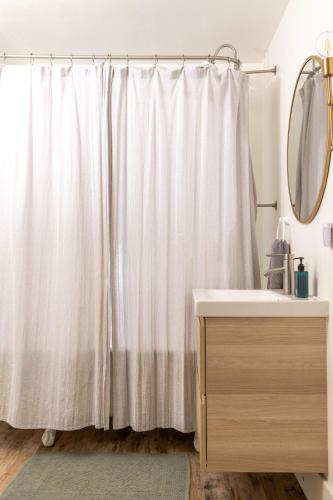 a bathroom with a white shower curtain and a sink at Its Back Historic Flat in Downtown Boise in Boise