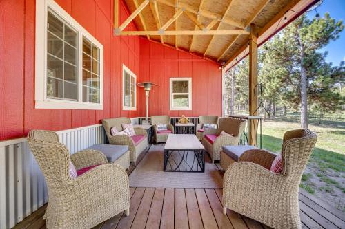 a porch with chairs and a table on a red wall at 13 Mi to USAFA Peaceful Colorado Springs Getaway! in Gleneagle
